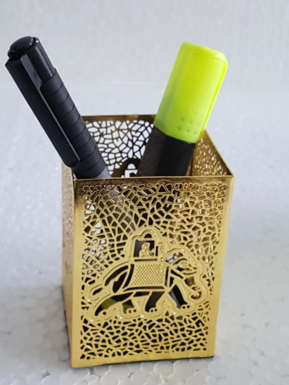 Gold filigree brass pen stand with an elephant motif, holding a pen and a highlighter