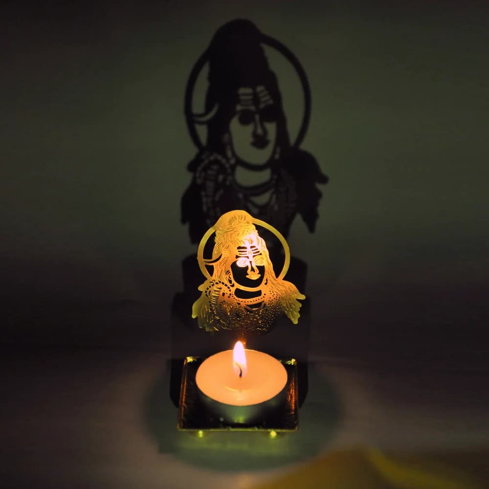 A lit shadow diya casting a large Shiva silhouette on the wall behind it