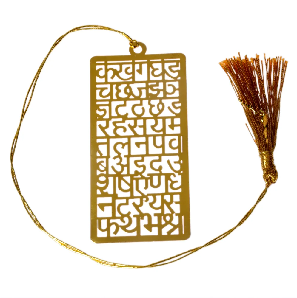 Die-cut gold-tone bookmark of the full Devanagari consonant chart cut as a grid of letters, on a gold cord with a tassel