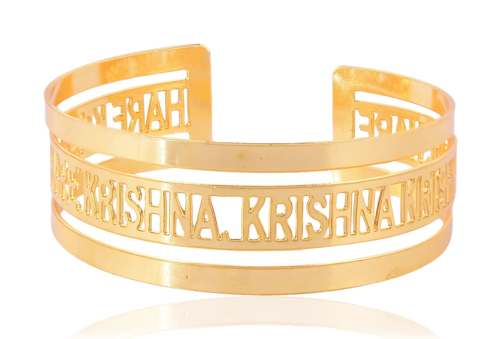Open gold-plated cuff bangle pierced with HARE KRISHNA in Roman capitals, shot square on at eye level with HARE repeating along the narrow upper band