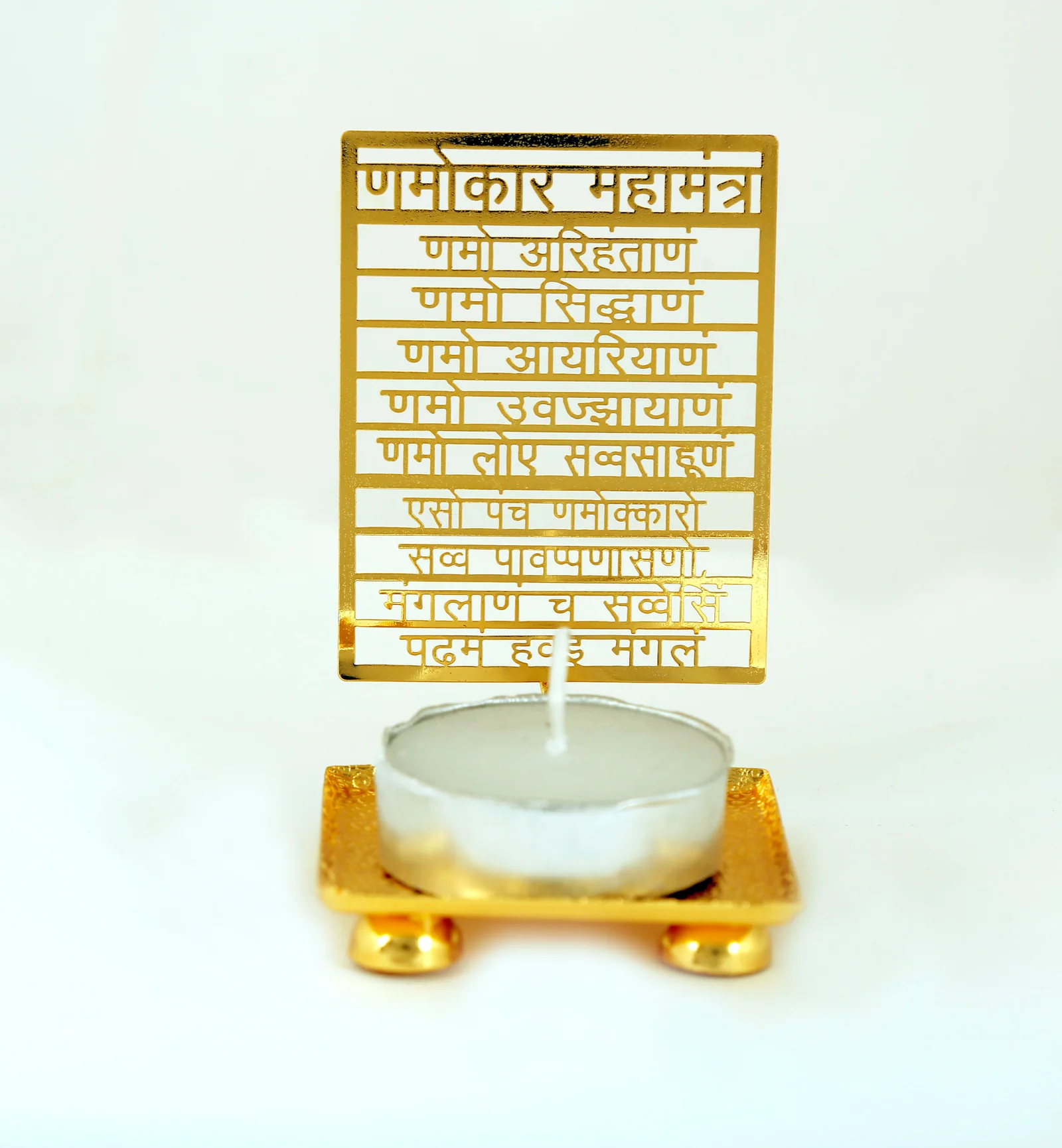 Gold tealight holder cut as a skeletonised leaf carrying the Namokar Mahamantra, standing on a footed tray, unlit on white