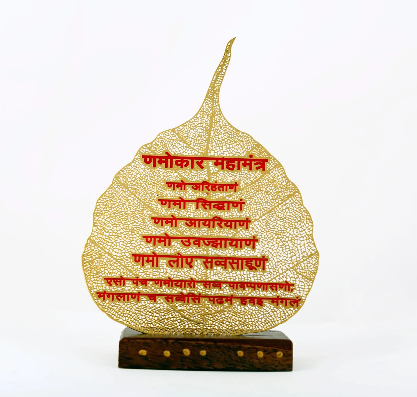 Gold skeletonised peepal leaf with a long drawn tip, carrying the Namokar Mahamantra in red Devanagari, on a studded wooden base