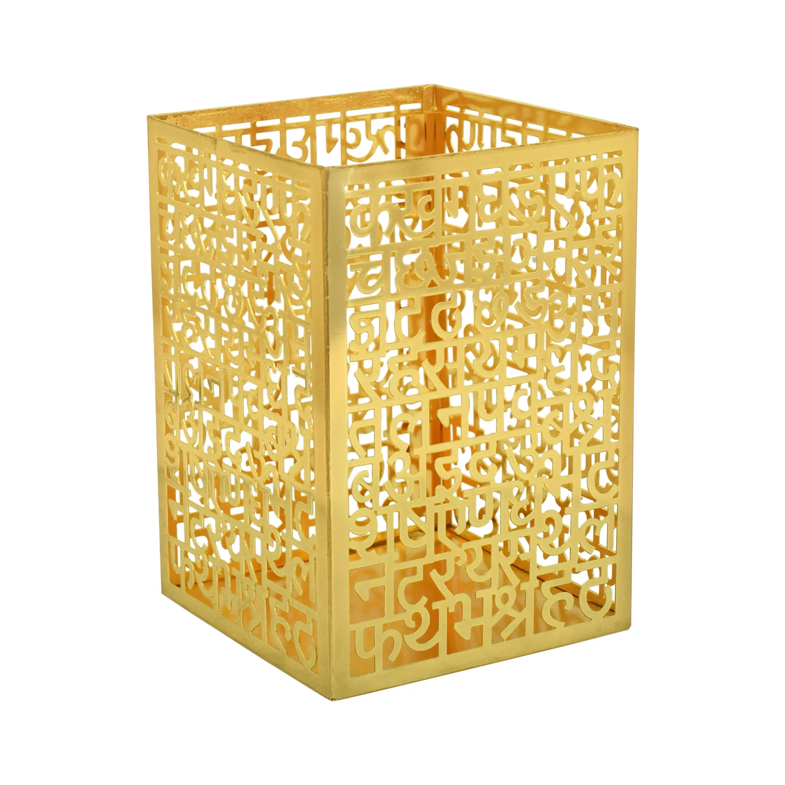 Gold-tone brass pen stand cut as a grid of Devanagari letters, shot three-quarter so two lettered faces and the open top are visible