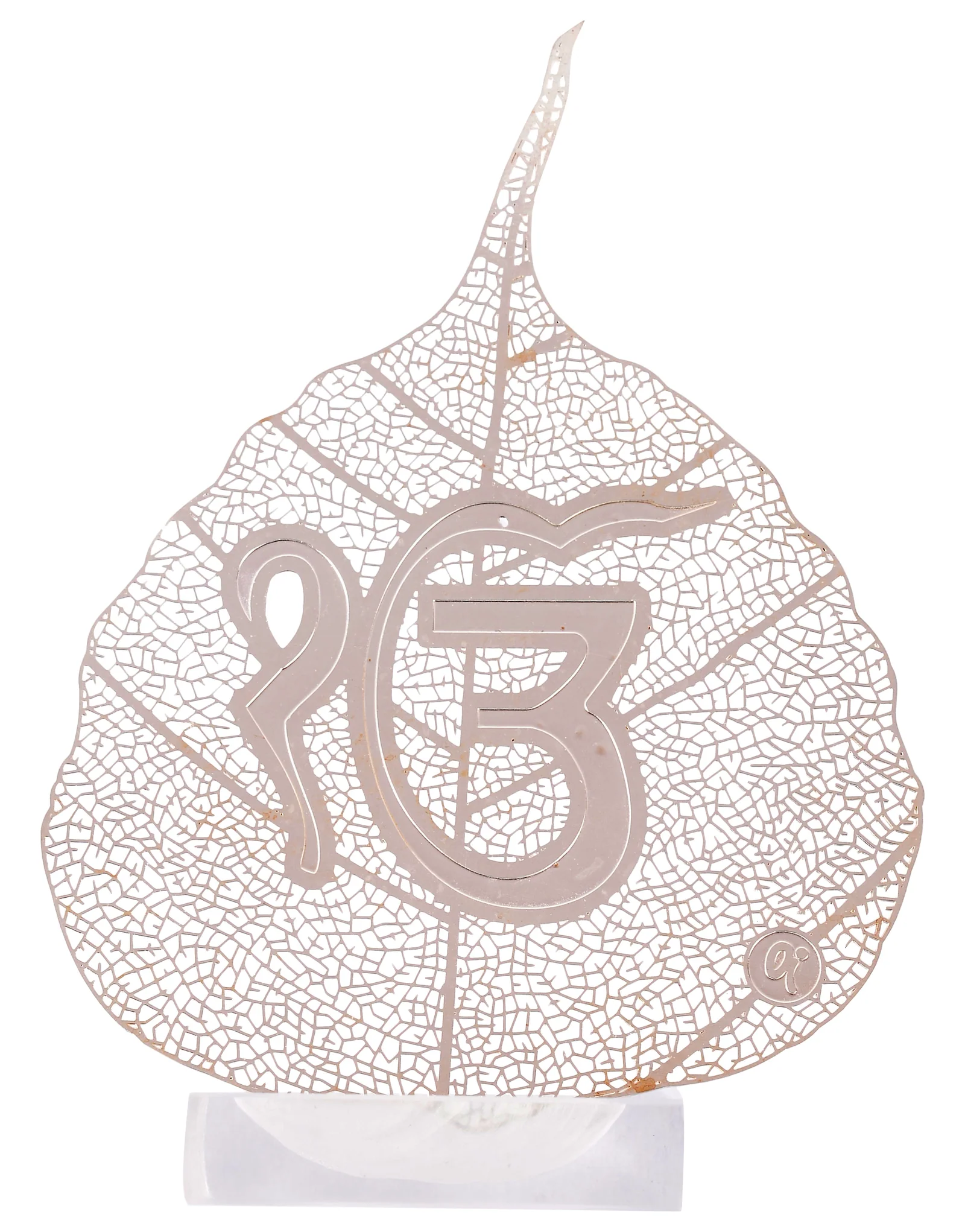 Silver skeletonised peepal leaf engraved with the Ek Onkar symbol in Gurmukhi, standing in a clear acrylic pedestal