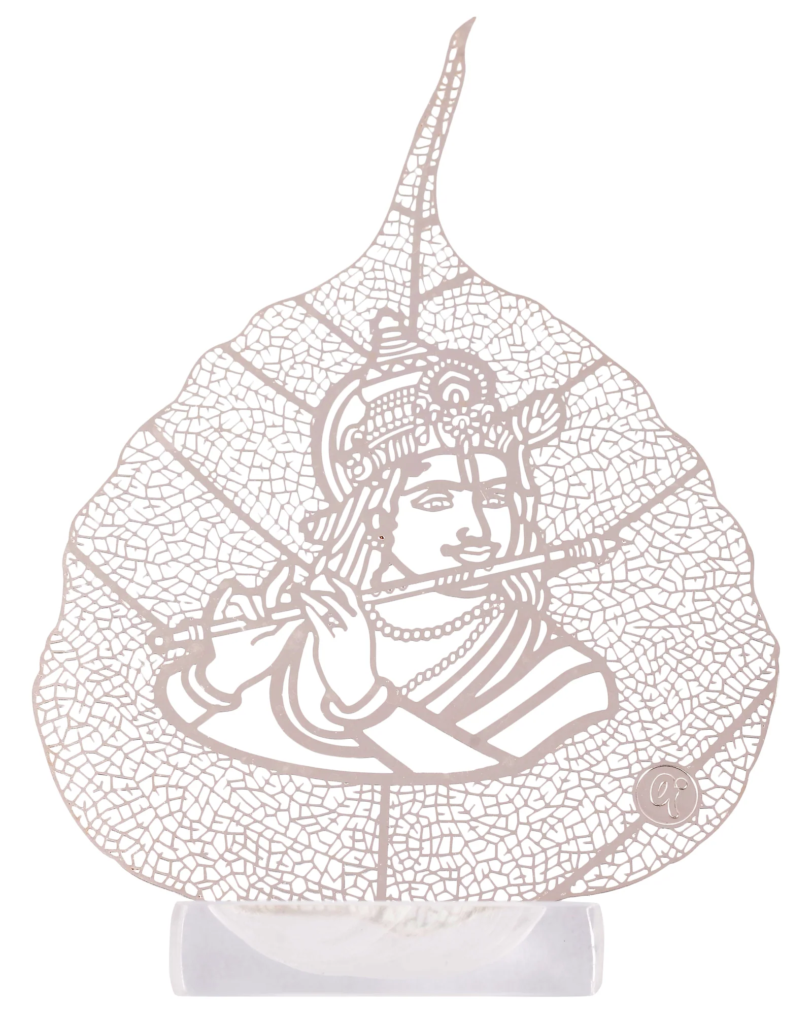 Silver skeletonised peepal leaf engraved with a crowned Krishna at his flute, standing in a clear acrylic pedestal