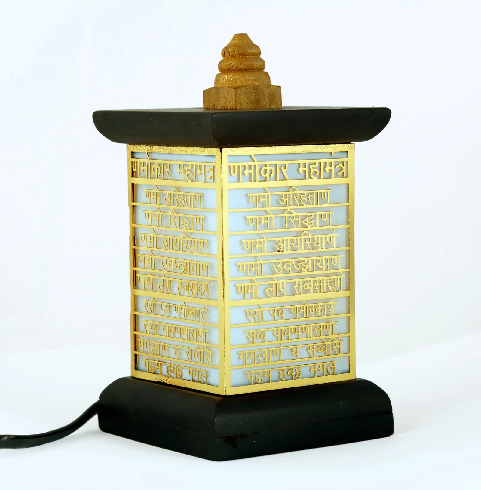 Wooden table lamp with a pierced gold panel carrying the Namokar Mahamantra in Devanagari, unlit on white