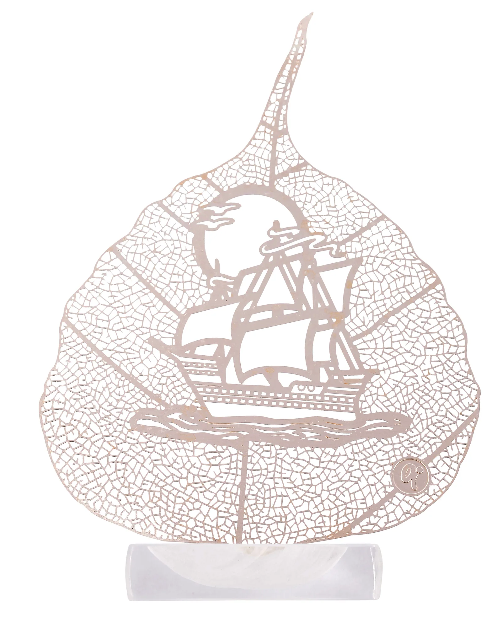 Silver skeletonised peepal leaf engraved with a square-rigged ship under full sail beneath a low sun, in a clear acrylic pedestal